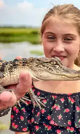 Young girl holding baby alligator