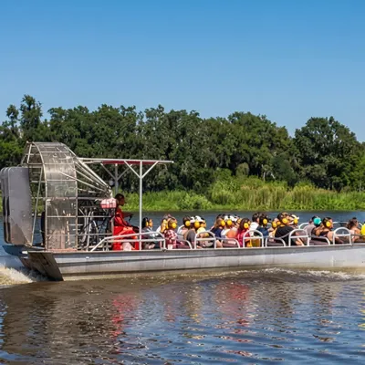 Large airboat full of passengers wearing ear protection cruising a Louisiana waterway near New Orleans